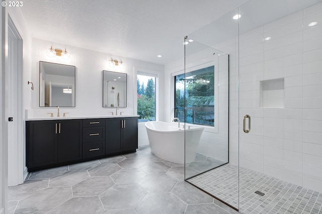 bathroom featuring dual sinks, tile floors, large vanity, independent shower and bath, and a textured ceiling