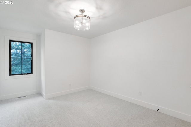 empty room with a notable chandelier and carpet floors