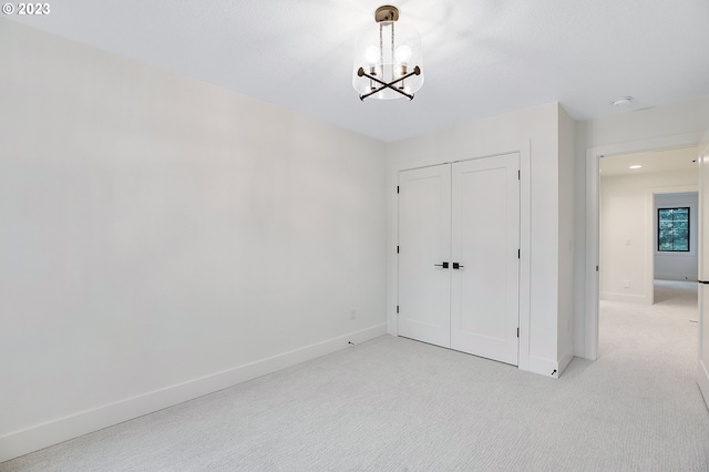 unfurnished bedroom with a notable chandelier, light carpet, and a closet