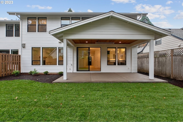 back of house with a patio and a lawn