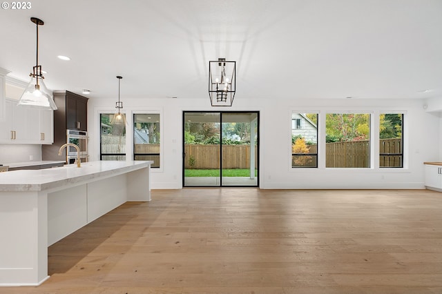 kitchen featuring dark brown cabinetry, a healthy amount of sunlight, decorative light fixtures, and light wood-type flooring