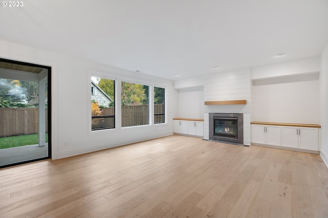 unfurnished living room featuring a healthy amount of sunlight, light hardwood / wood-style flooring, and a tile fireplace