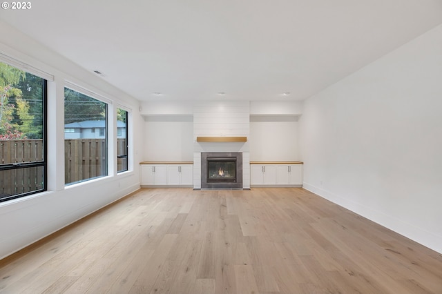 unfurnished living room featuring light hardwood / wood-style floors and a tile fireplace