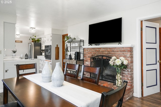 dining area featuring dark wood-type flooring and a fireplace