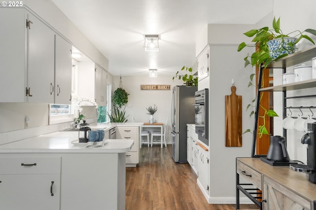 kitchen with kitchen peninsula, stainless steel refrigerator, and white cabinetry