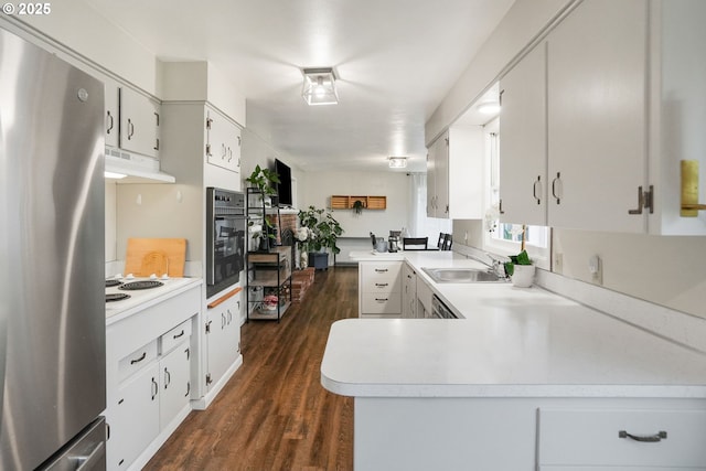 kitchen with white cabinets, kitchen peninsula, stainless steel fridge, and oven