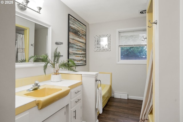 bathroom with a tub, a baseboard radiator, wood-type flooring, and vanity