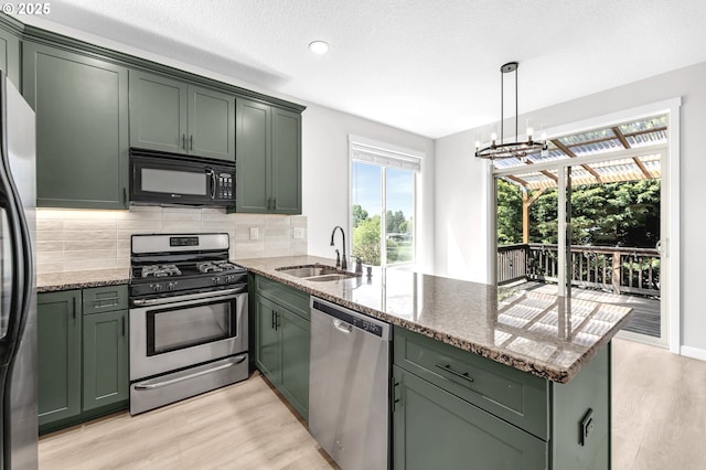 3707 NE Minnehaha St, Vancouver, WA 98661 - kitchen featuring a sink, a peninsula, stainless steel appliances, green cabinetry, and light wood-type flooring
