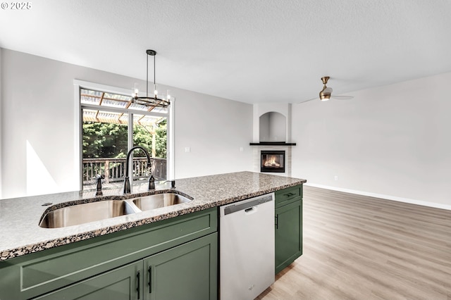 3707 NE Minnehaha St, Vancouver, WA 98661 - kitchen with stainless steel dishwasher, light wood finished floors, a glass covered fireplace, a sink, and green cabinetry