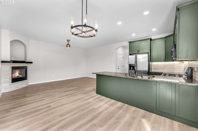 3707 NE Minnehaha St, Vancouver, WA 98661 - kitchen with a sink, a peninsula, green cabinetry, arched walkways, and appliances with stainless steel finishes