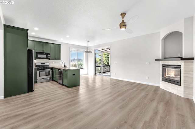 3707 NE Minnehaha St, Vancouver, WA 98661 - kitchen featuring ceiling fan, open floor plan, green cabinetry, a tile fireplace, and stainless steel appliances