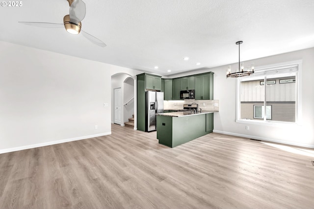 3707 NE Minnehaha St, Vancouver, WA 98661 - kitchen with a peninsula, stainless steel appliances, ceiling fan with notable chandelier, green cabinetry, and arched walkways