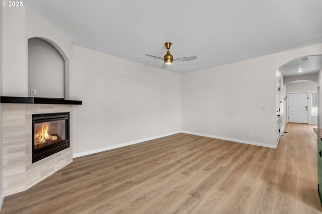 3707 NE Minnehaha St, Vancouver, WA 98661 - unfurnished living room with baseboards, light wood finished floors, a tiled fireplace, ceiling fan, and arched walkways