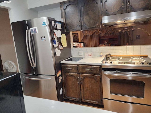 kitchen with dark brown cabinets, backsplash, stainless steel refrigerator, and range