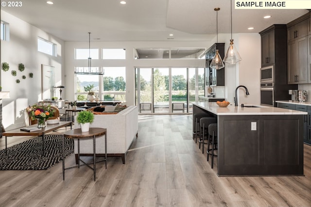 kitchen with decorative light fixtures, stainless steel appliances, a center island with sink, and sink