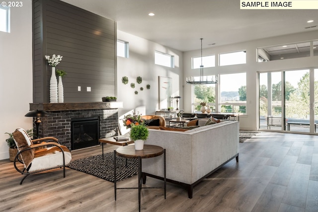 living room featuring hardwood / wood-style floors, a high ceiling, and a brick fireplace