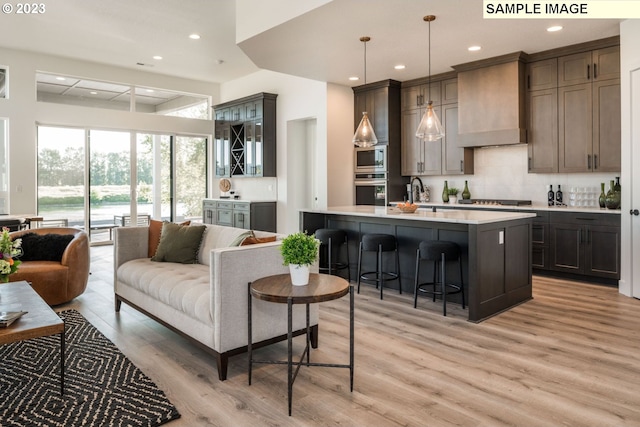 bar with pendant lighting, custom exhaust hood, backsplash, light wood-type flooring, and appliances with stainless steel finishes