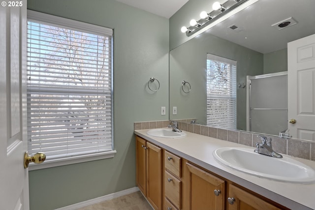 full bathroom with a sink, visible vents, baseboards, and double vanity