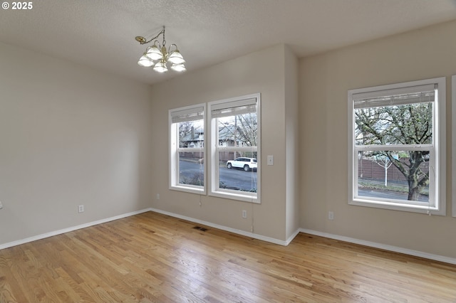 unfurnished dining area featuring visible vents, plenty of natural light, an inviting chandelier, and light wood-style flooring