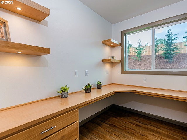 unfurnished office featuring dark hardwood / wood-style floors and built in desk