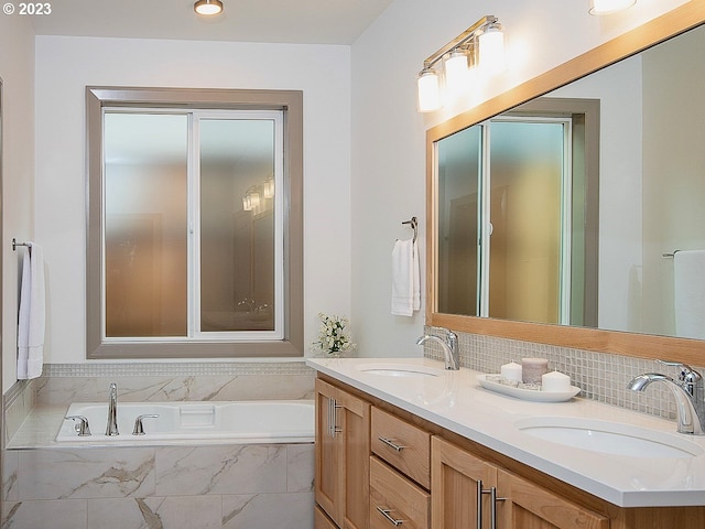 bathroom with tiled bath, dual sinks, and vanity with extensive cabinet space