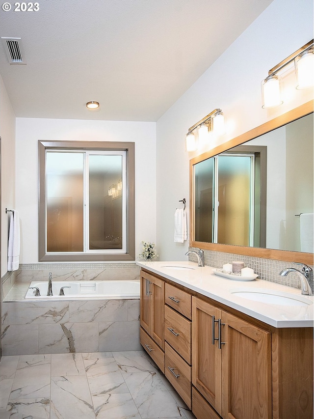 bathroom featuring tile floors, dual vanity, and tiled tub