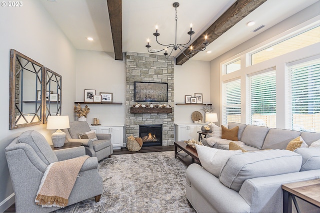 living room featuring an inviting chandelier, a stone fireplace, wood-type flooring, and a wealth of natural light