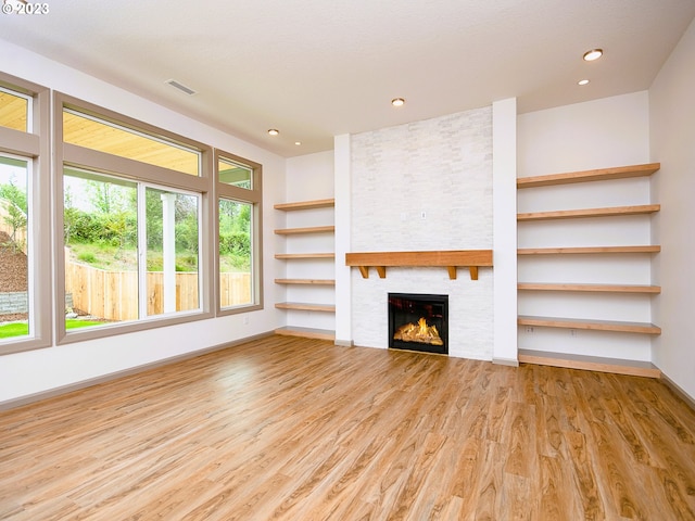 unfurnished living room featuring light hardwood / wood-style floors, a fireplace, and a wealth of natural light