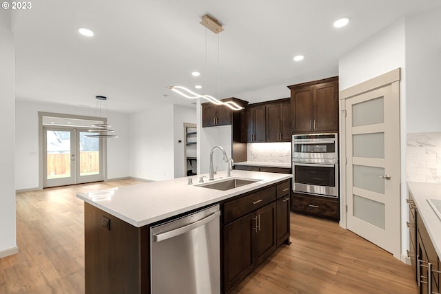 kitchen with pendant lighting, a center island with sink, appliances with stainless steel finishes, and sink