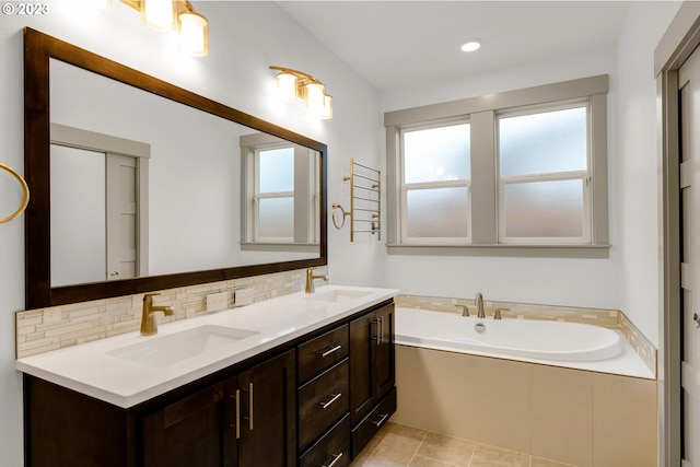 bathroom featuring oversized vanity, double sink, tasteful backsplash, a relaxing tiled bath, and tile floors