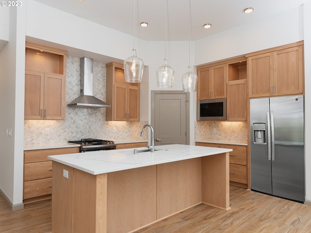 kitchen featuring stainless steel fridge, tasteful backsplash, a center island with sink, and wall chimney range hood