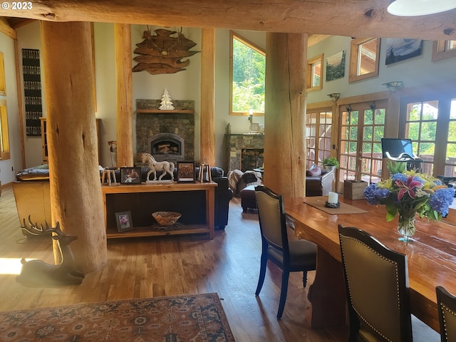 dining room with french doors, a healthy amount of sunlight, hardwood / wood-style floors, and a stone fireplace