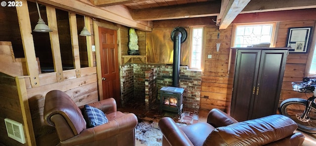 interior space featuring a wood stove, beam ceiling, and wooden walls