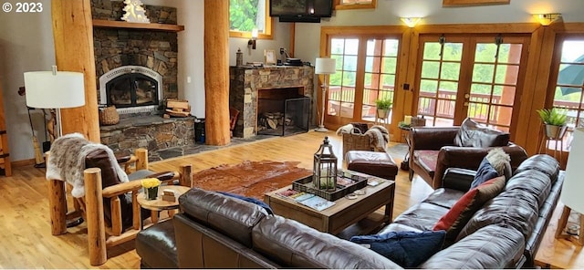 living room featuring a stone fireplace, light wood-type flooring, and french doors