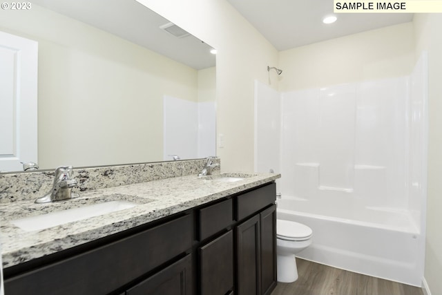 full bathroom with double sink, hardwood / wood-style floors,  shower combination, toilet, and oversized vanity