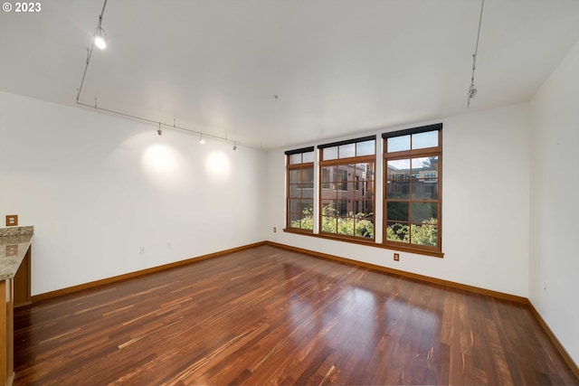 spare room with rail lighting and dark hardwood / wood-style floors