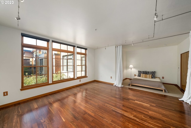 unfurnished living room with dark wood-type flooring and rail lighting