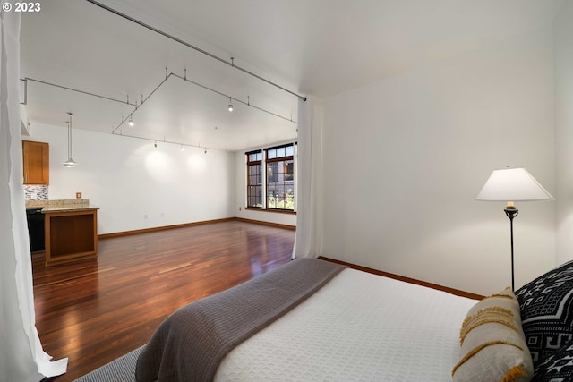 bedroom with dark wood-type flooring and track lighting