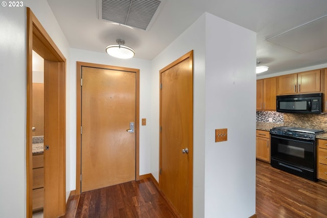 interior space featuring dark hardwood / wood-style flooring, light stone countertops, tasteful backsplash, and black appliances