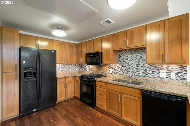 kitchen featuring sink, dark hardwood / wood-style flooring, light stone countertops, black appliances, and tasteful backsplash