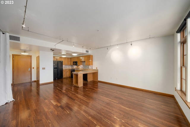 unfurnished living room with dark hardwood / wood-style flooring, sink, and track lighting