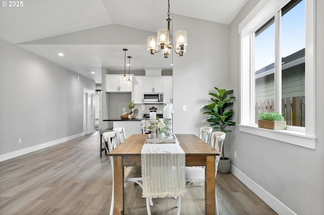 dining area featuring vaulted ceiling, light wood-type flooring, and an inviting chandelier