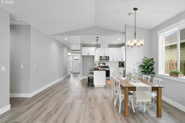 dining area featuring a chandelier, light hardwood / wood-style floors, and vaulted ceiling