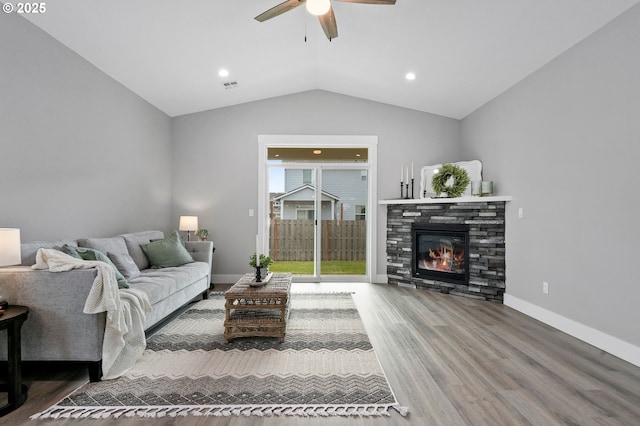 living room featuring a fireplace, hardwood / wood-style flooring, vaulted ceiling, and ceiling fan