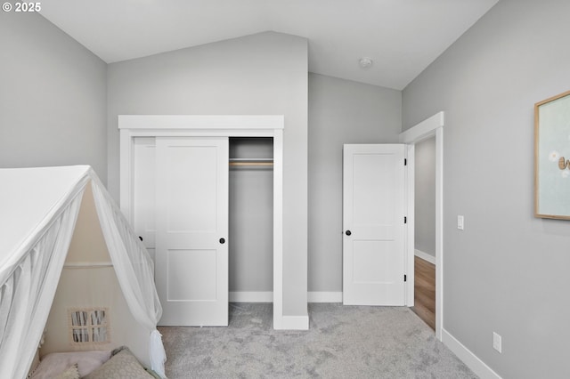 unfurnished bedroom featuring a closet, lofted ceiling, and light carpet