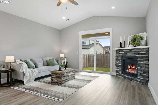 living room featuring hardwood / wood-style flooring, ceiling fan, a fireplace, and vaulted ceiling