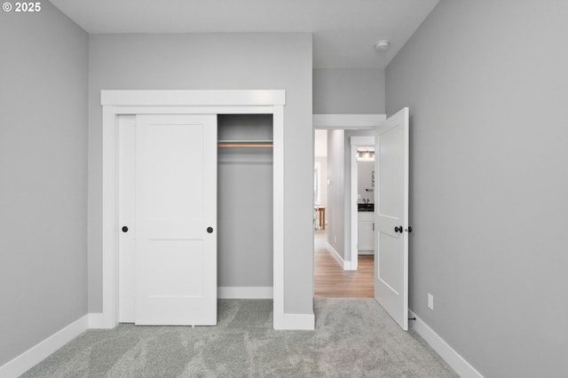 unfurnished bedroom with light colored carpet and a closet