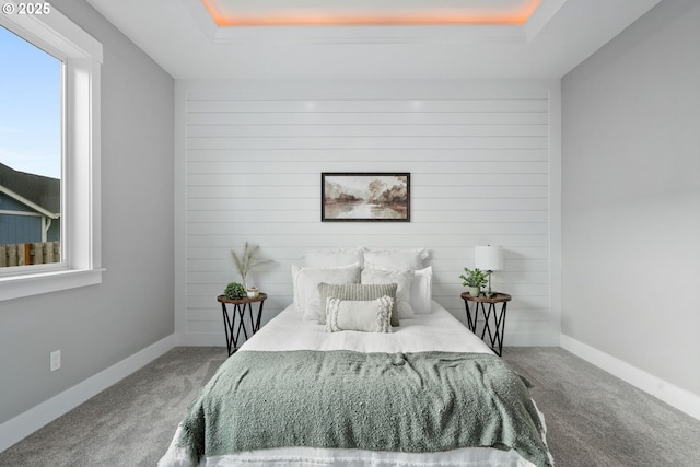 bedroom featuring a tray ceiling and carpet flooring