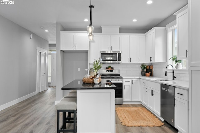 kitchen featuring white cabinetry, sink, a center island, and appliances with stainless steel finishes