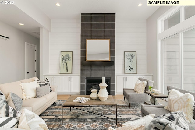 living room featuring a tiled fireplace and hardwood / wood-style flooring